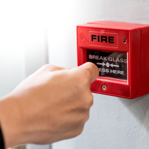 Image of a hand about to break the glass on an fire safety box