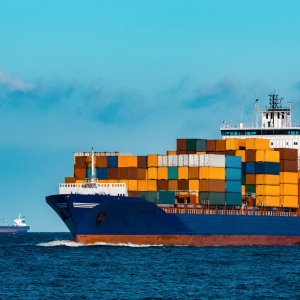 Photo of a marine cargo ship on the sea with exhaust fumes coming out of its chimney.
