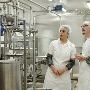Photo of a female and male in white overalls in a industrial catering kitchen